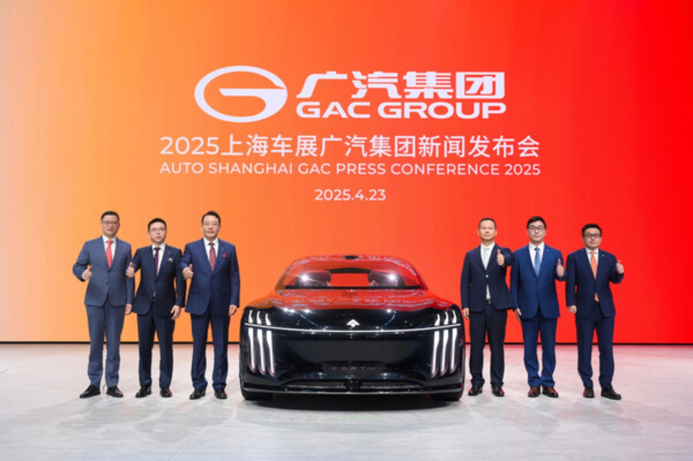 Sieben Männer in Anzügen stehen auf einer Bühne neben einem futuristischen Auto mit leuchtendem Kühlergrill, vor einem roten Hintergrund mit dem Logo der GAC Group und Informationen zur Auto Shanghai Pressekonferenz 2025.