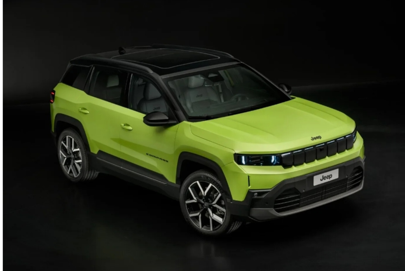 Ein SUV des Modells Jeep Compass in Limettengrün mit schwarzem Dach steht in einem Studio und ist so ausgerichtet, dass Front und Seite sichtbar sind.