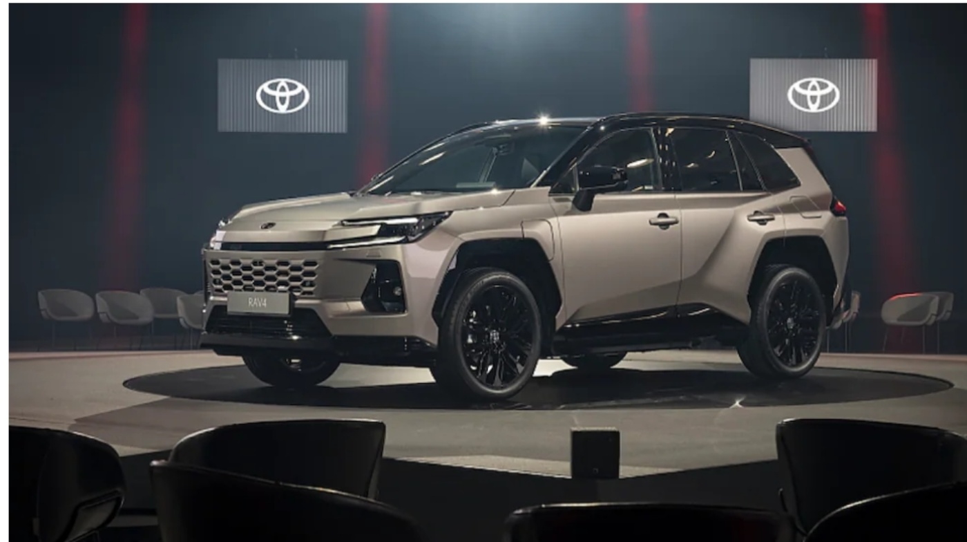 Ein beigefarbener Toyota SUV mit schwarzen Felgen auf einer runden Bühne unter Scheinwerfern bei einer Indoor-Veranstaltung.