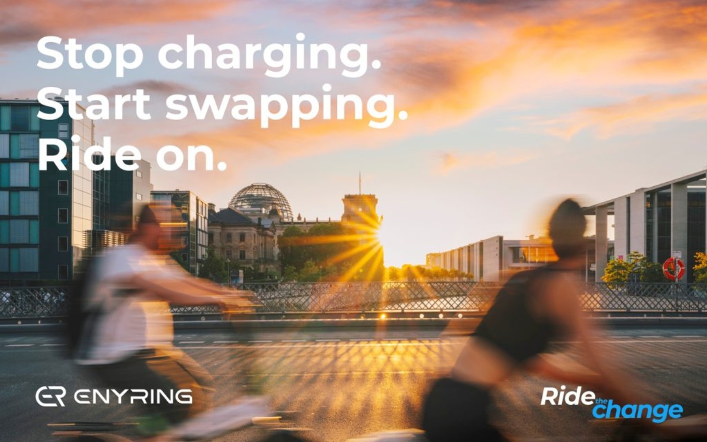 Zwei Personen auf E-Scootern in Bewegungsunschärfe vor dem Reichstagsgebäude bei Sonnenuntergang, mit dem Text „Stop charging. Start swapping. Ride on.“