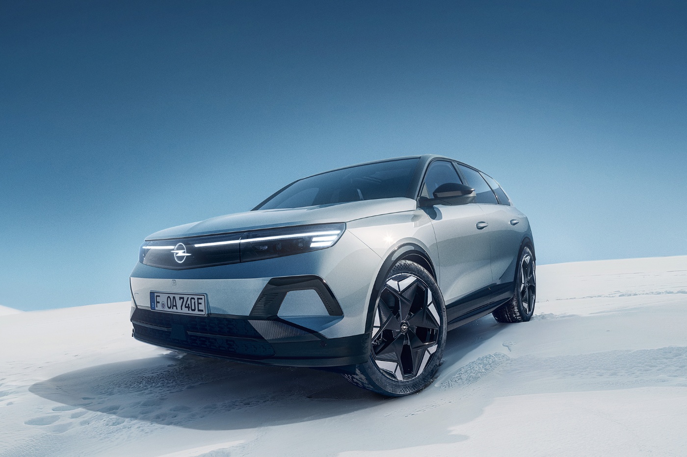 A silver SUV stands on a snowy landscape under a clear blue sky.