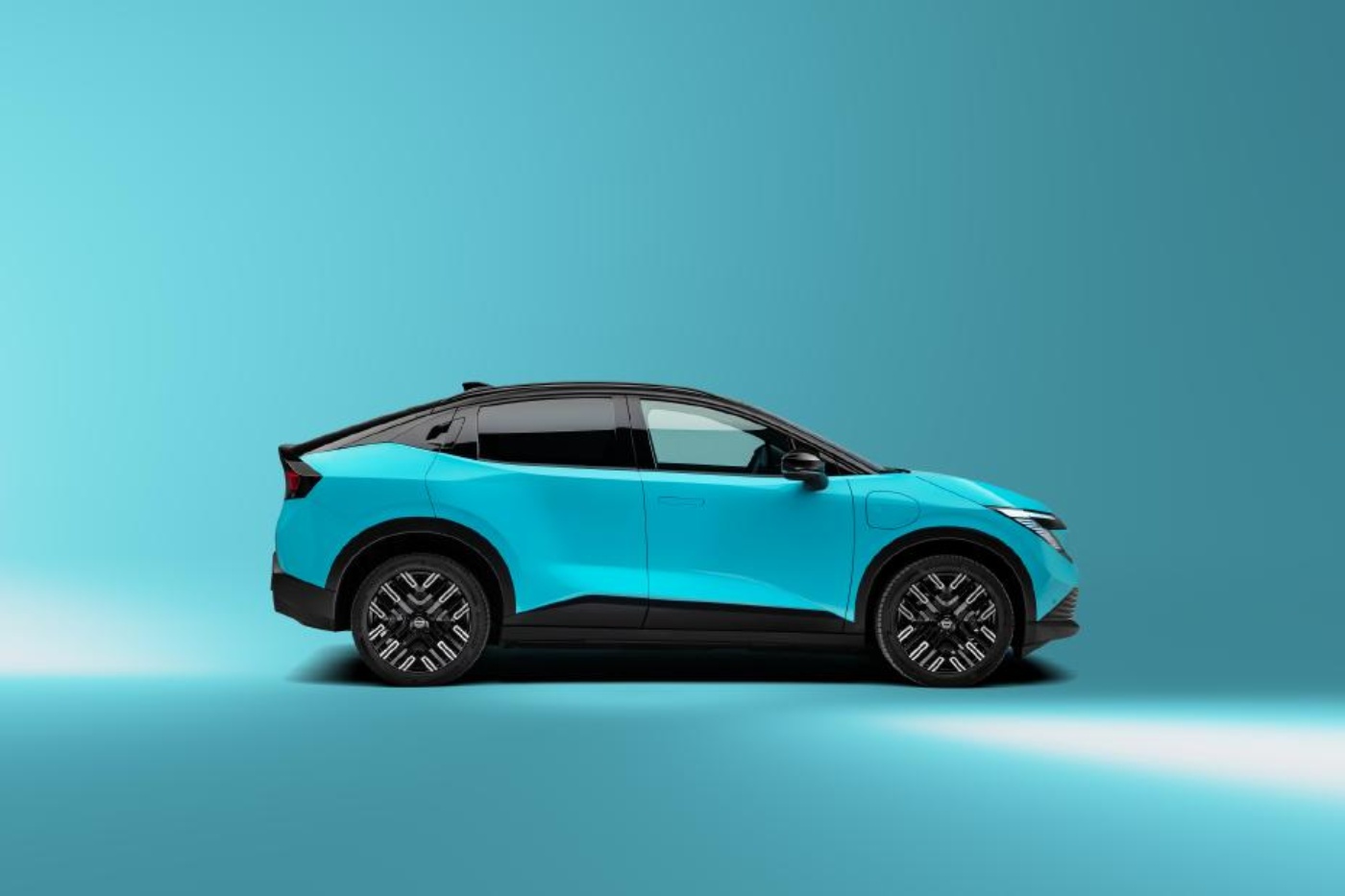 Seitenansicht eines türkisfarbenen Elektro-SUVs vor blauem Hintergrund in Studioaufnahme.