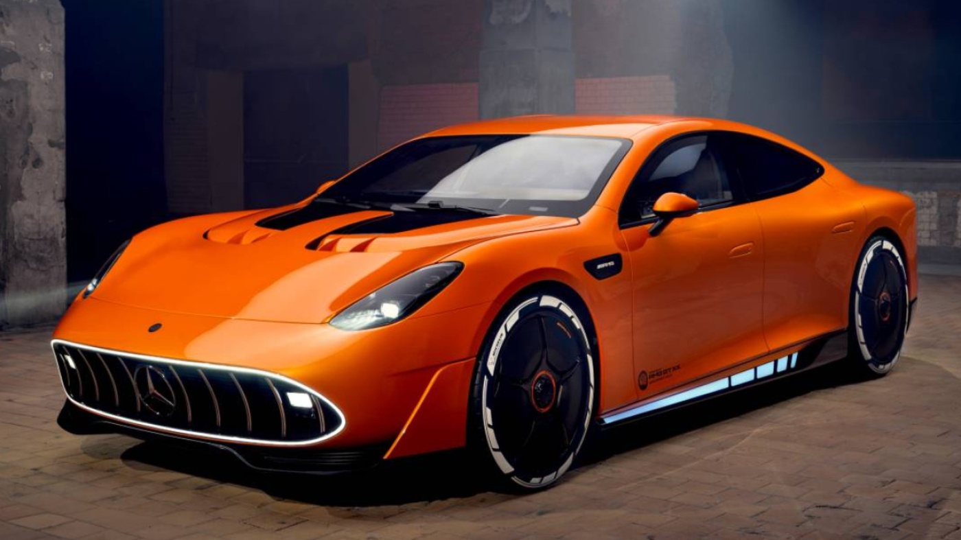 Orange concept sports car with sleek design and illuminated grille in an industrial setting.