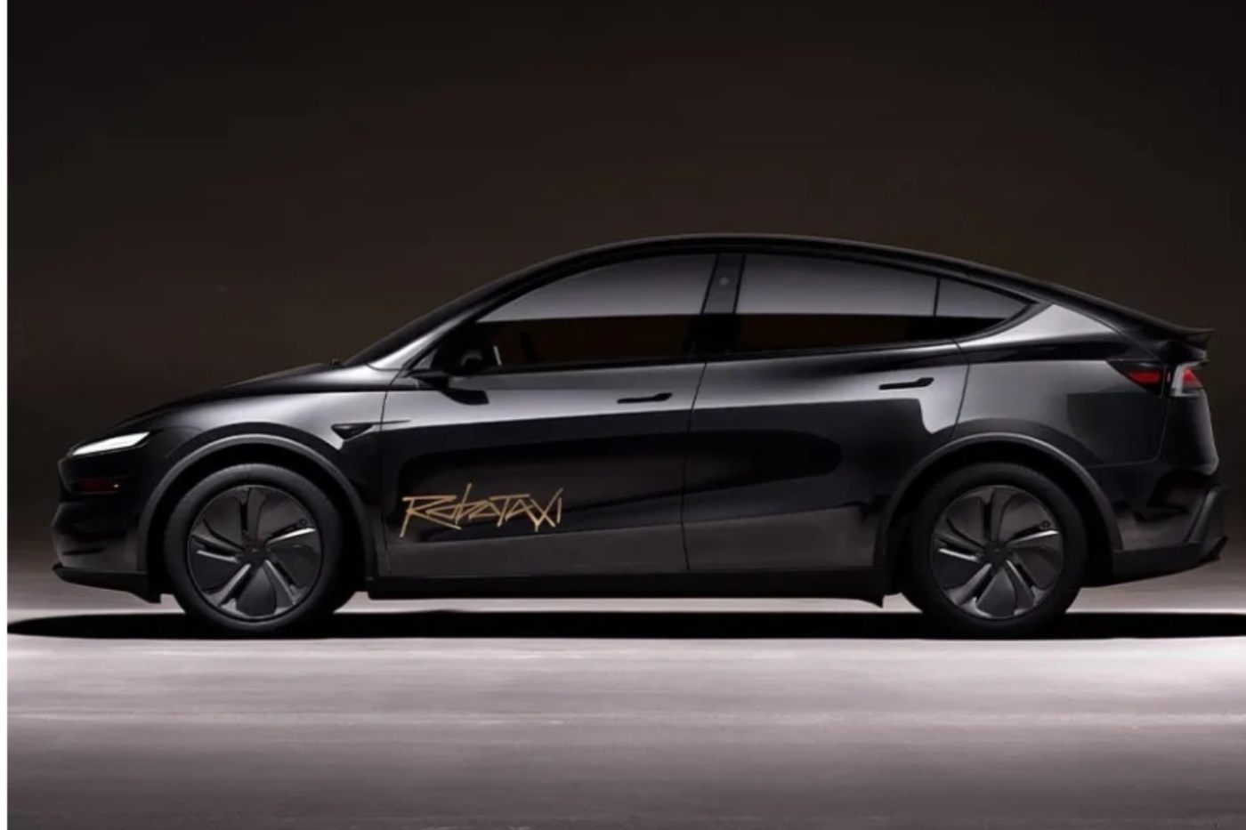 Side view of a black electric car with 'Robotaxi' written on the door in a dark studio setting.
