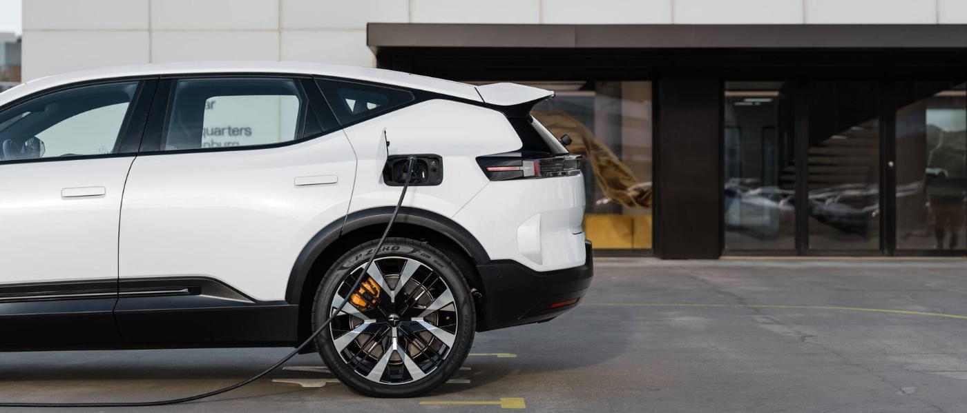Ein weißer Elektro-SUV lädt vor einem modernen Gebäude mit großen Glastüren.