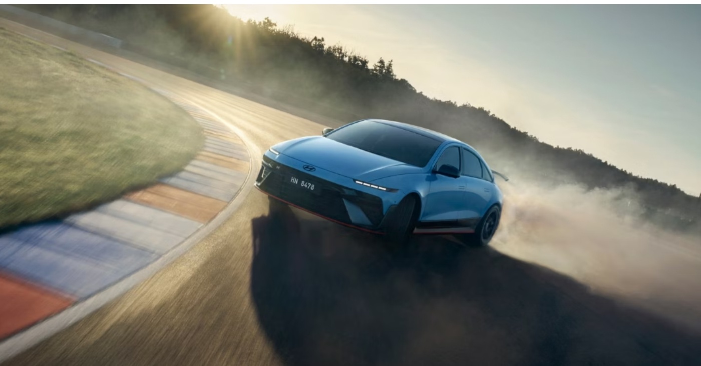 Blue sports car drifting on a racetrack, kicking up smoke on a sharp curve.