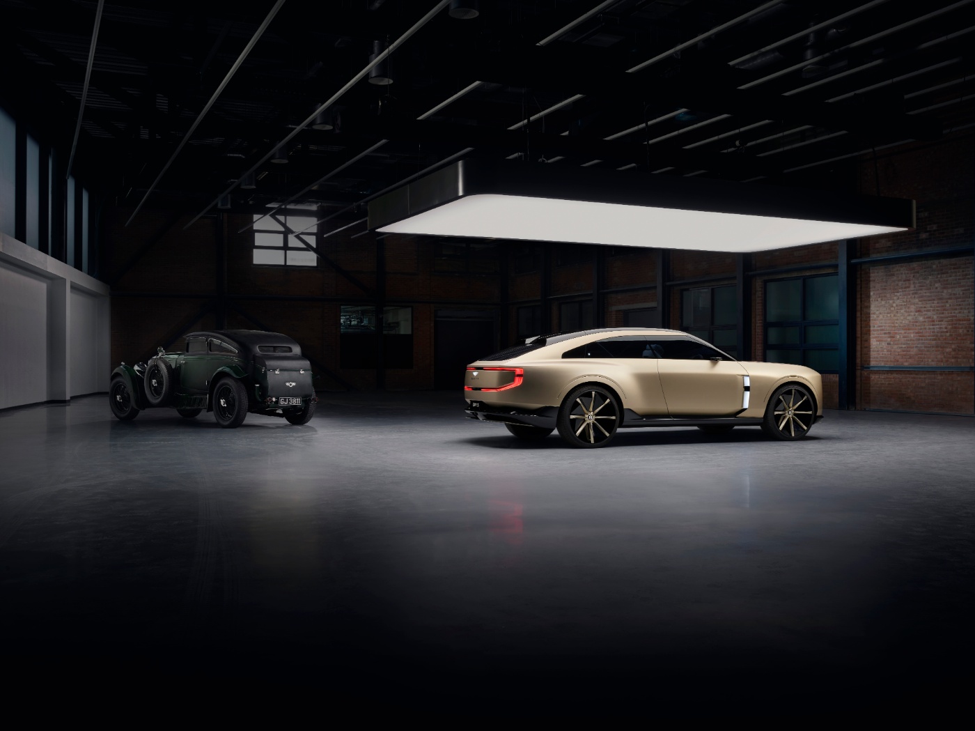 Vintage car and modern coupe side by side in a dimly lit industrial showroom.