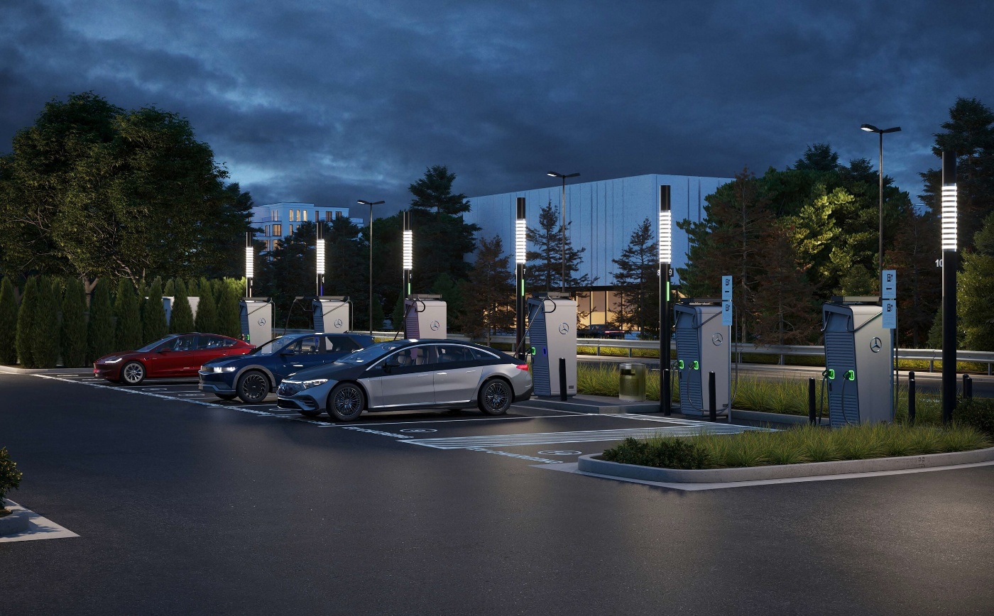 Elektroautos laden bei beleuchteten Mercedes-Benz-Stationen auf einem modernen Parkplatz bei Dämmerung.