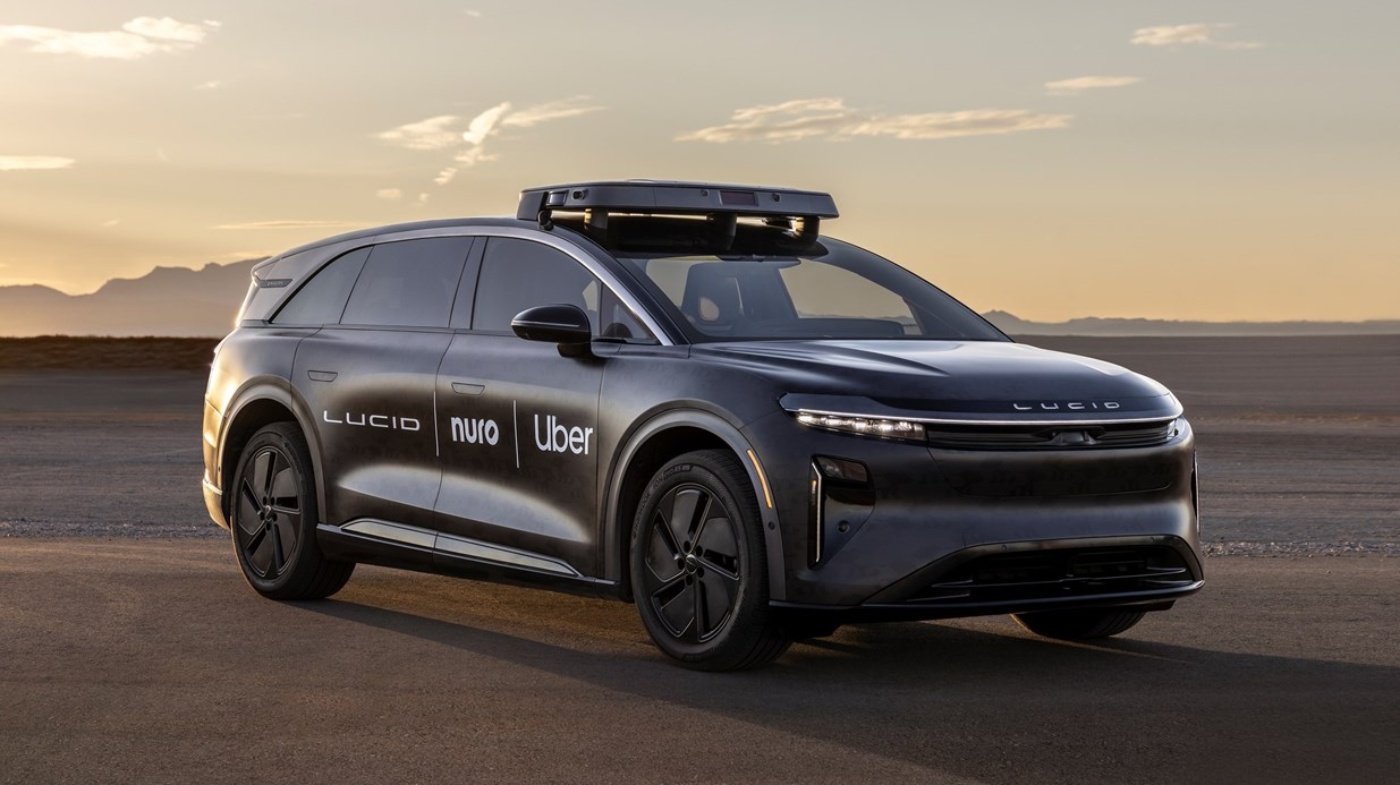 Autonomer Lucid-SUV mit Dachsensor und Logos von Uber und Nuro bei Sonnenuntergang geparkt.