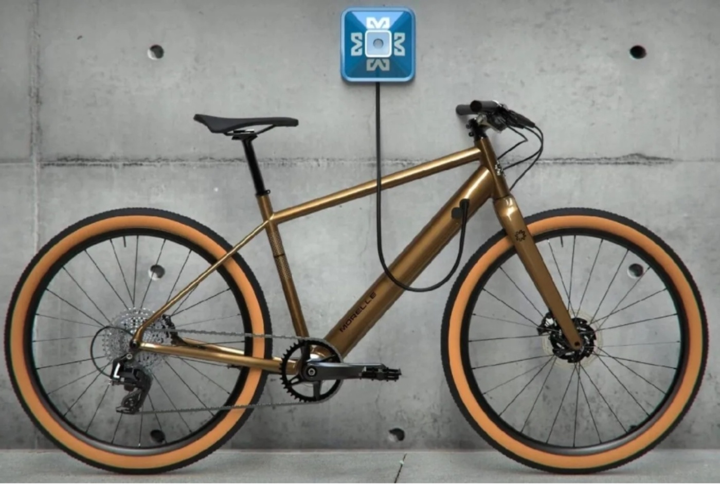 Goldenes Morelle E-Bike lädt an einer Wandladestation.