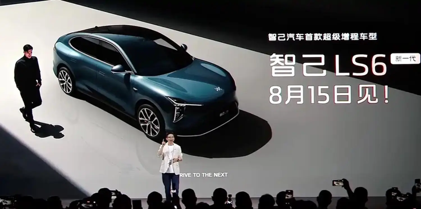 Presentation of the blue IM LS6 car with speakers on stage and large launch date text.