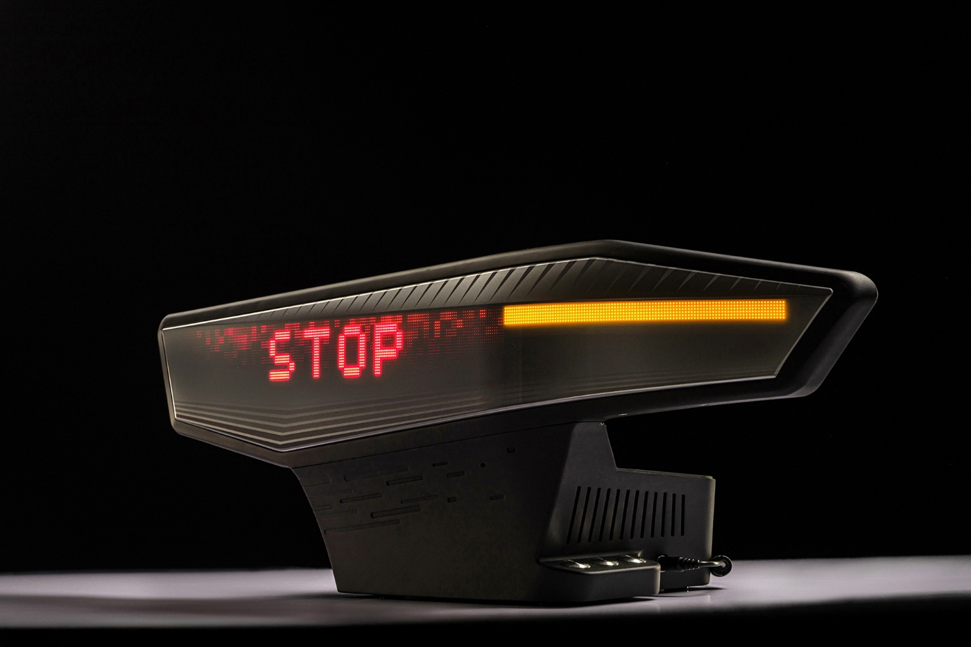 Illuminated automotive display unit with red "STOP" text and yellow indicator on a dark background.