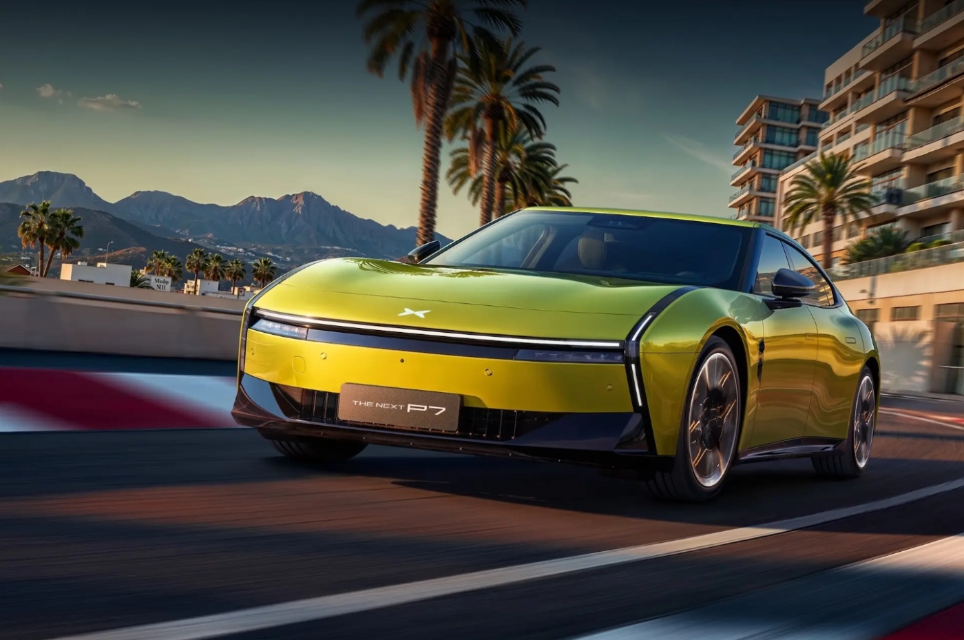 Green XPENG P7 concept car driving on a coastal road with palm trees and mountains in the background.