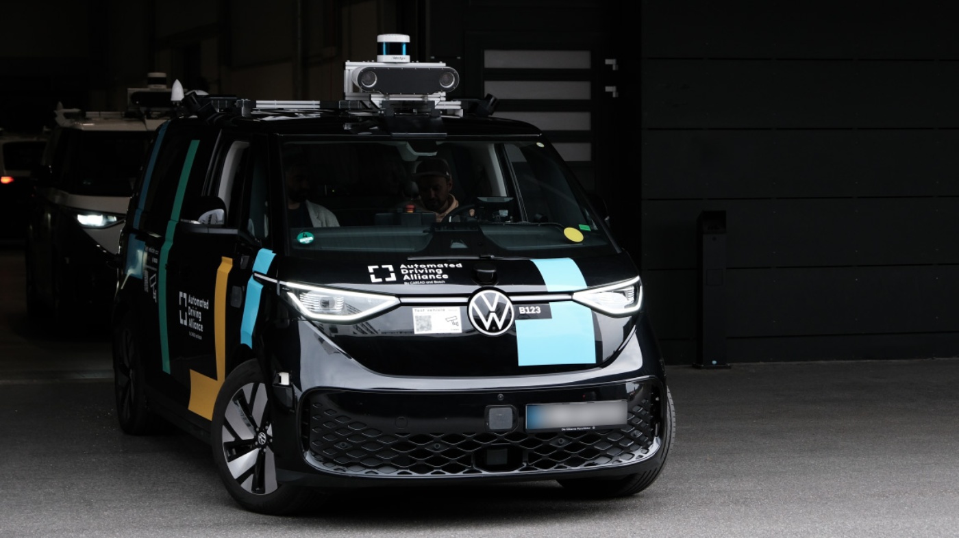 Black VW test vehicle with sensors for autonomous driving parked in front of a building.