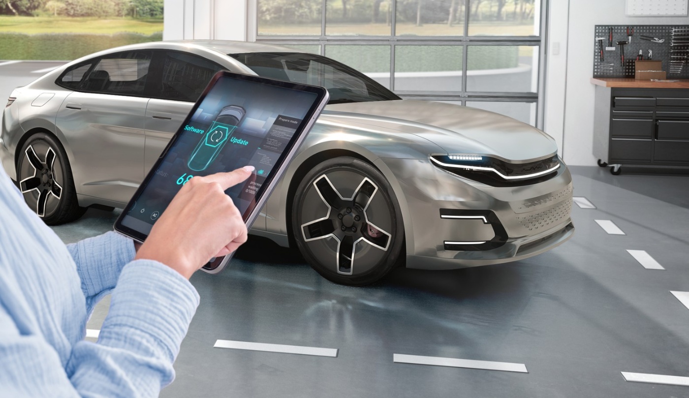 Person aktualisiert per Tablet die Software eines silbernen E-Autos in moderner Garage.