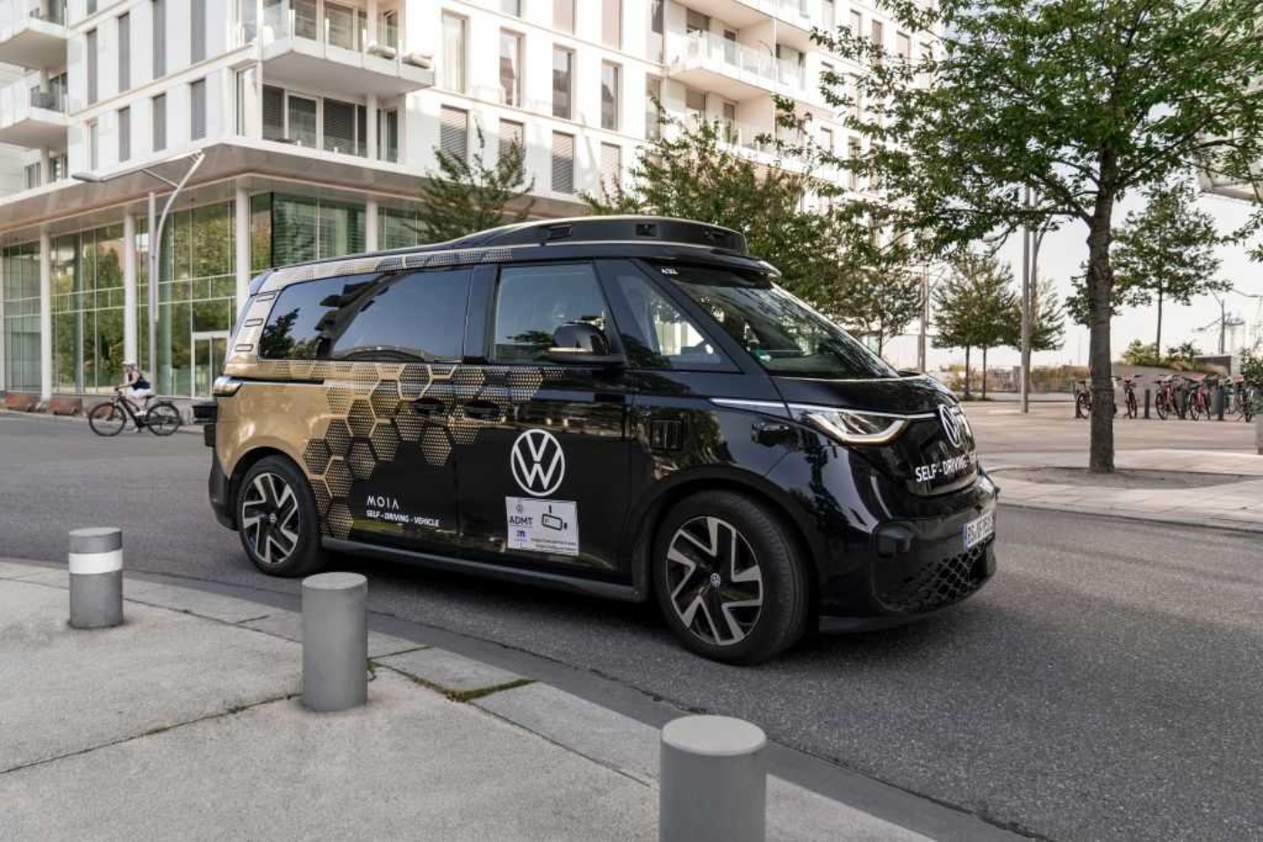 Schwarzer selbstfahrender VW-Van mit MOIA-Branding auf einer Stadtstraße.
