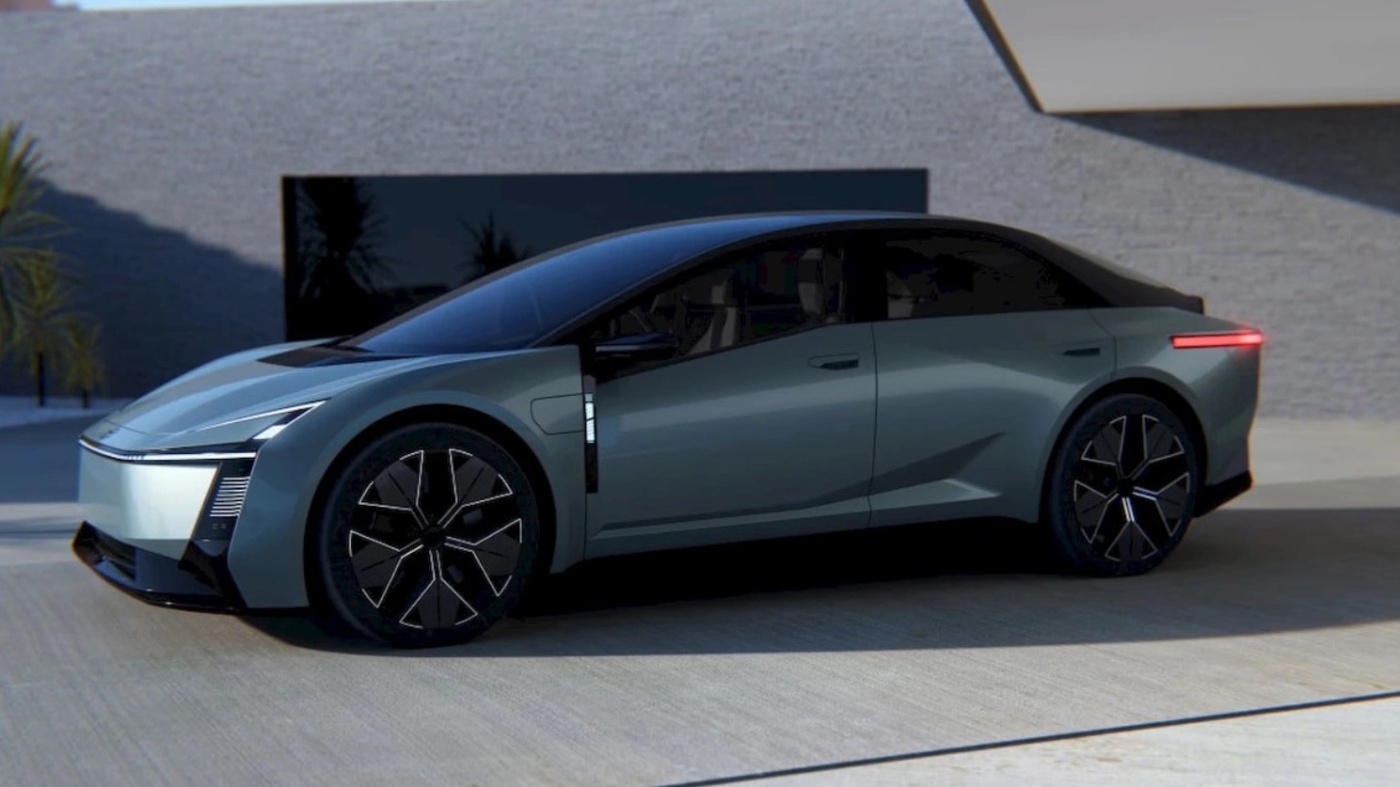 Side view of a gray Toyota Corolla with black wheels in front of a modern building.