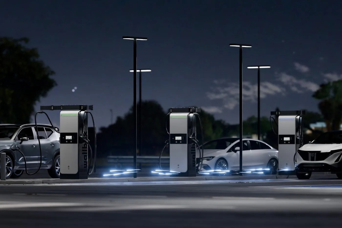 Three electric cars at three illuminated charging stations in an outdoor nighttime setting.