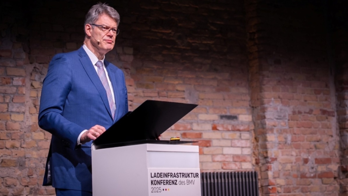 Man in a blue suit speaks at a podium during the Charging Infrastructure Conference 2025.
