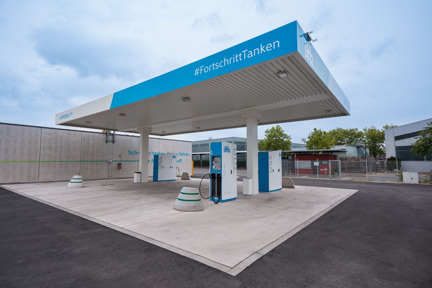 Modern hydrogen fueling station with H2 pumps under a roof and the hashtag #FortschrittTanken.