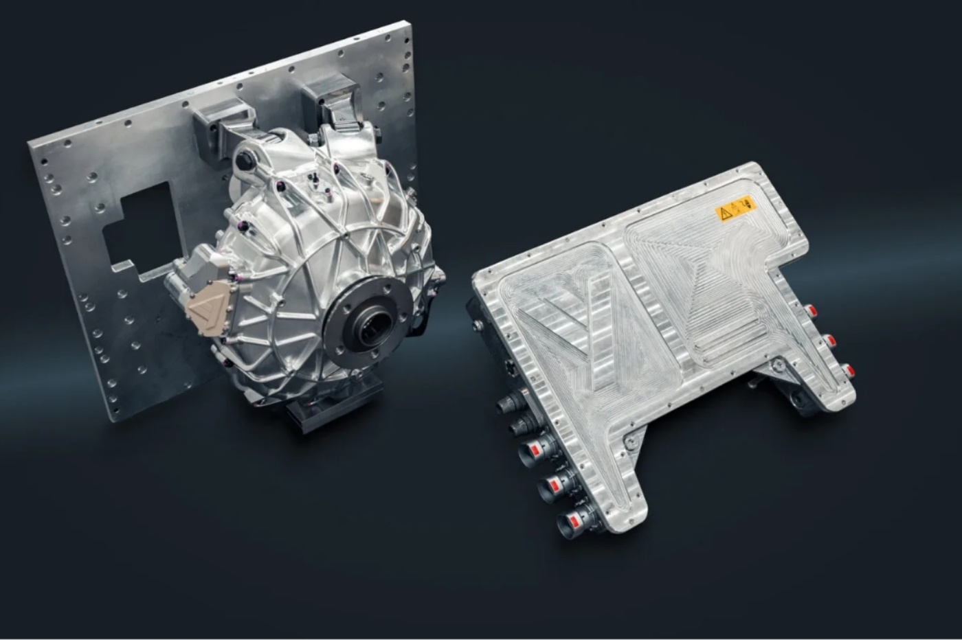Ein kompakter Elektromotor und eine Steuereinheit sind vor dunklem Hintergrund ausgestellt.