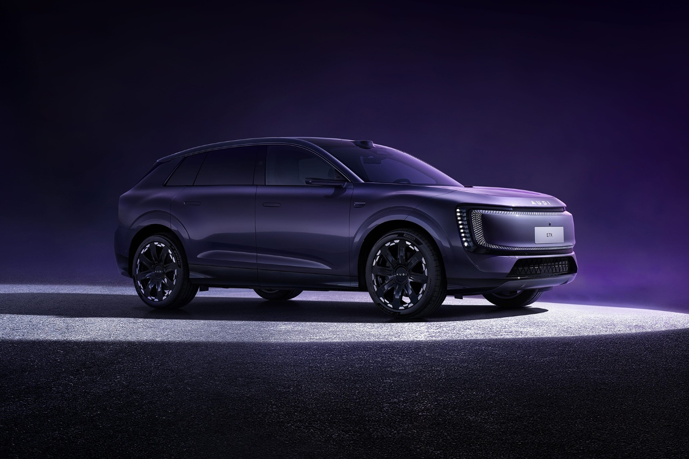 Ein dunkelviolettes Audi-SUV-Konzept steht auf einer beleuchteten Bühne vor violettem Hintergrund.