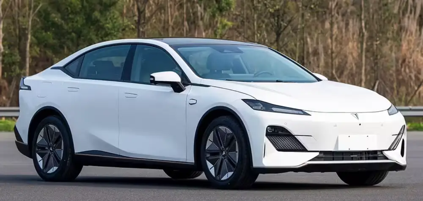 Eine weiße Elektro-Limousine steht auf einer Straße mit Bäumen im Hintergrund.