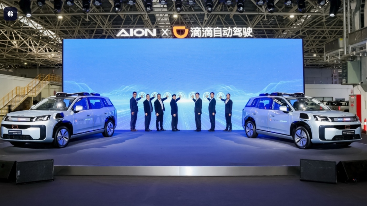 Acht Personen präsentieren zwei autonome SUVs auf einer Bühne mit digitalem Hintergrund.