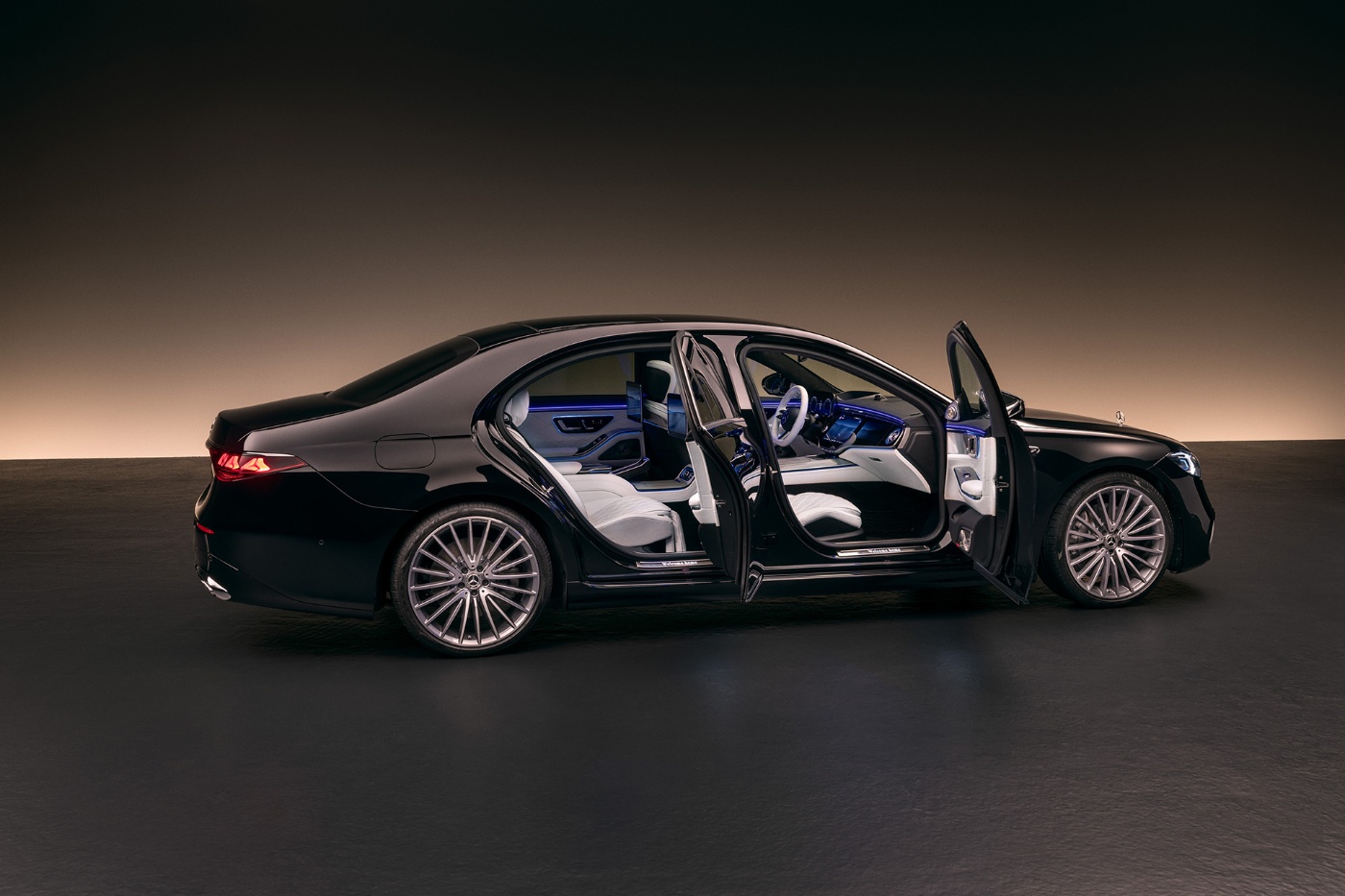 Eine schwarze Mercedes-Benz S-Klasse Limousine mit offenen Türen zeigt ein weiß-blau beleuchtetes Interieur.