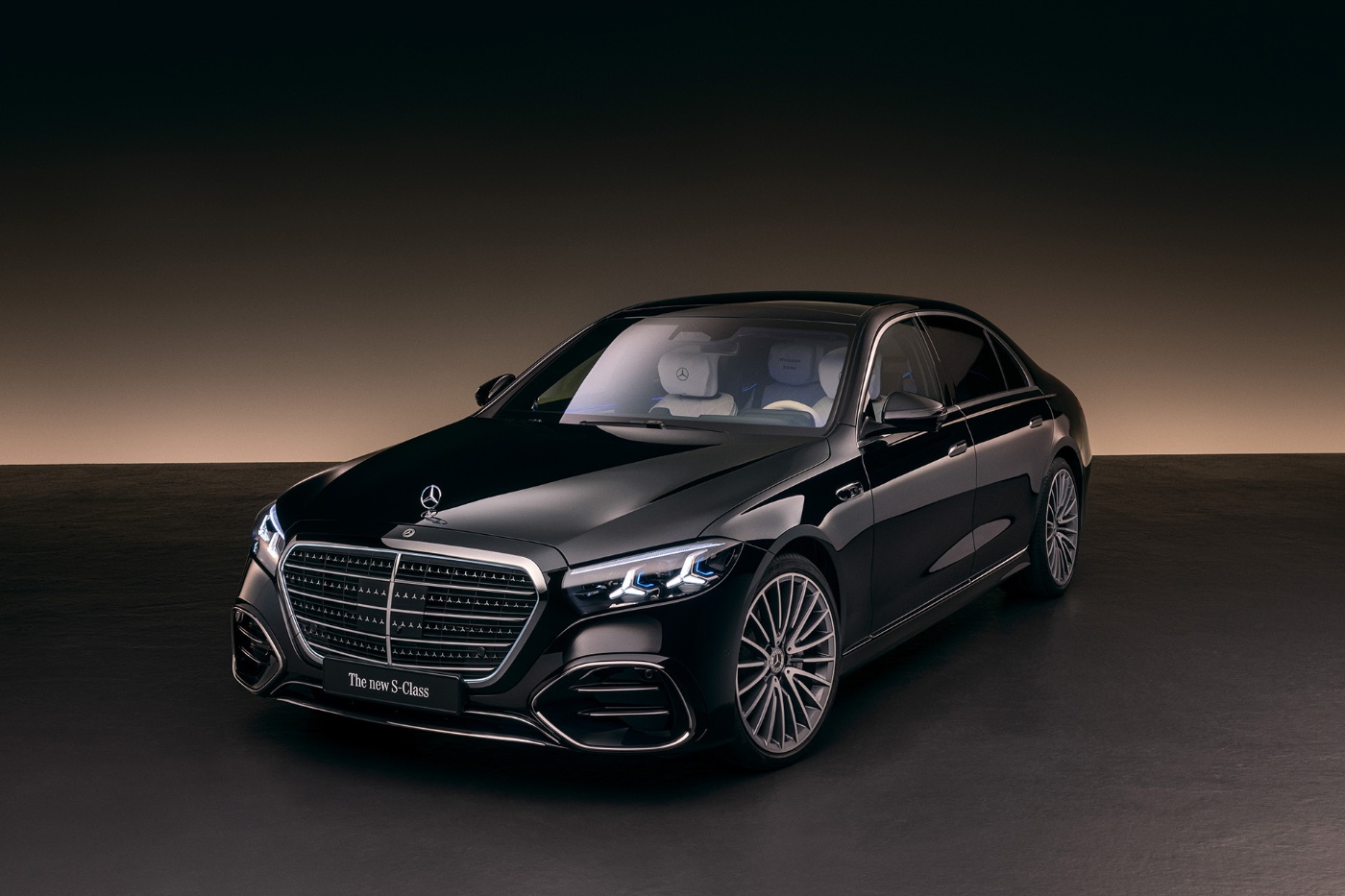 A black luxury sedan Mercedes-Benz S-Class is displayed in a studio with soft lighting.