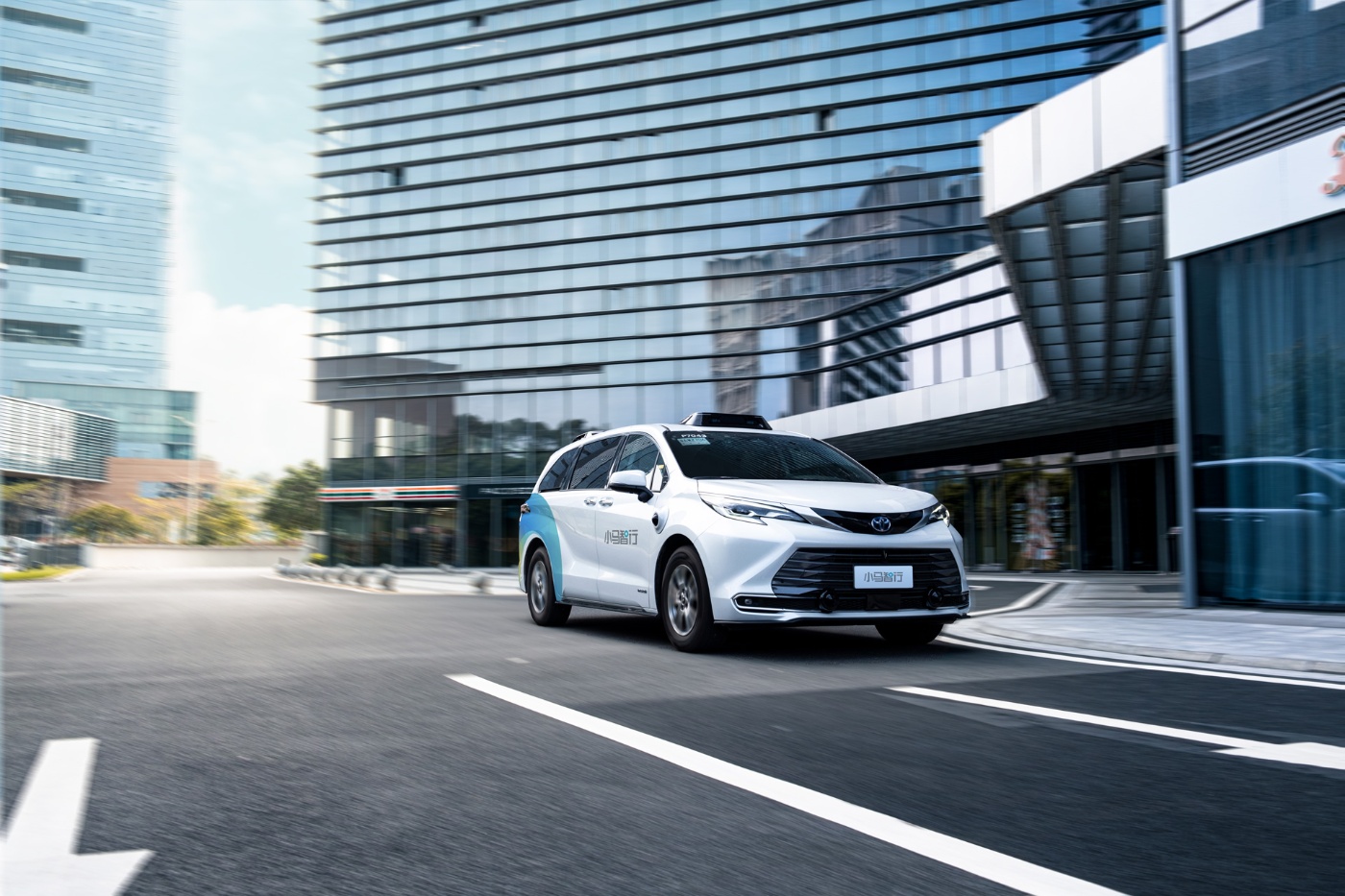 Autonomous minivan driving through modern city street.