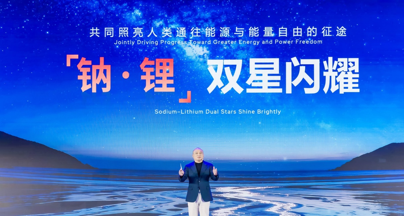 Man speaking on stage before large screen with energy slogan.