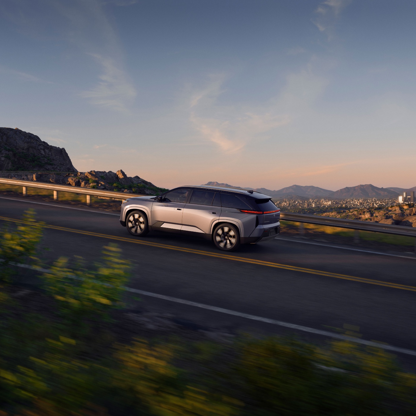 Electric SUV driving on mountain road at sunset.