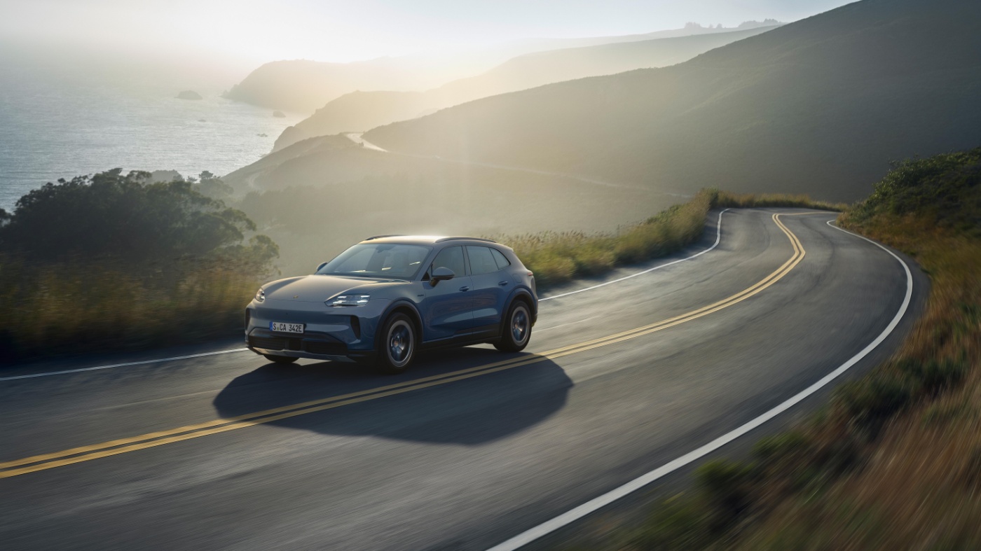 Porsche Cayenne S driving on a winding coastal road.