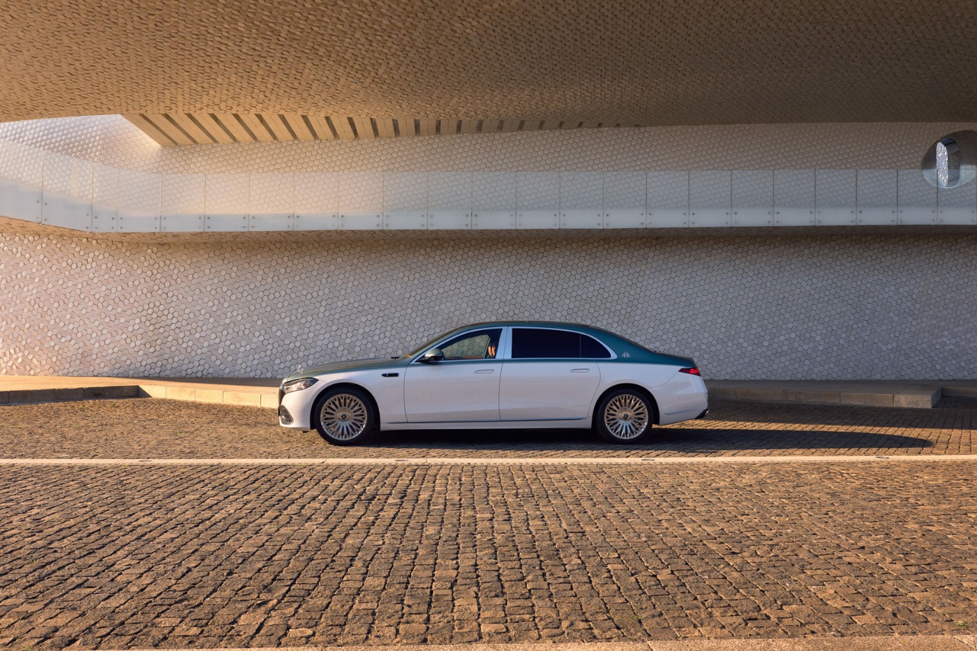 White Mercedes-Benz parked beside a textured modern building.