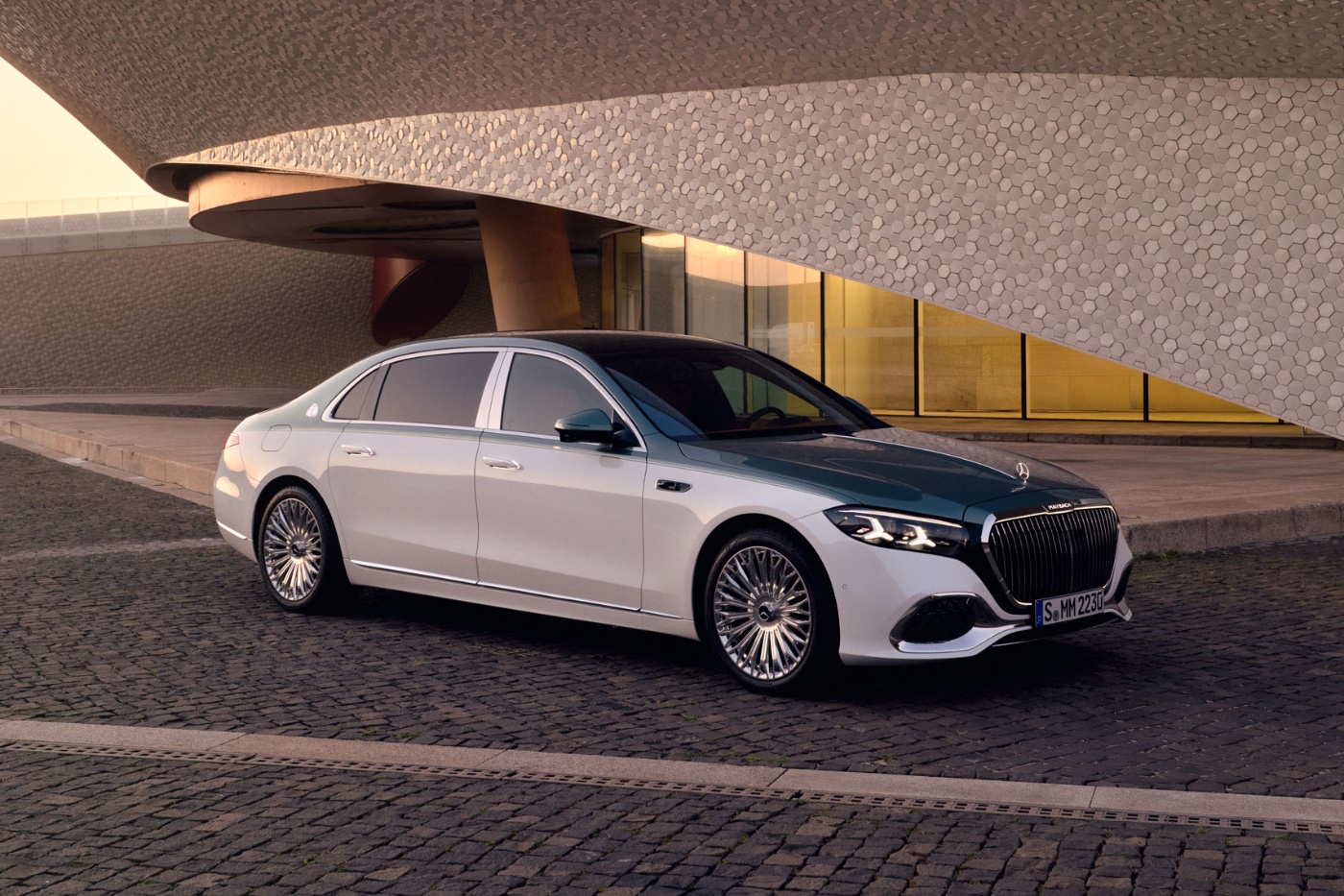 White Mercedes-Benz parked under a modern curved concrete structure.