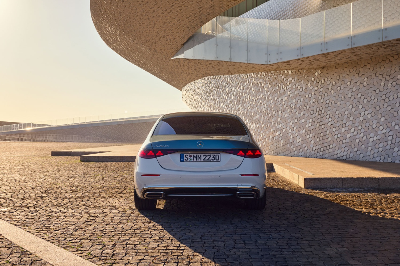 Rear view of a white Mercedes-Benz parked by a modern building.
