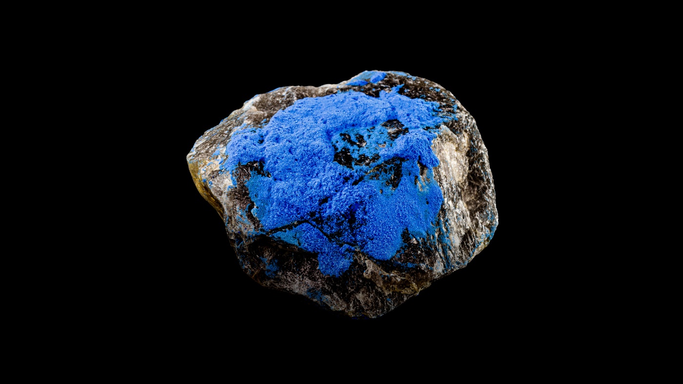 Blauer Mineralstein vor schwarzem Hintergrund.