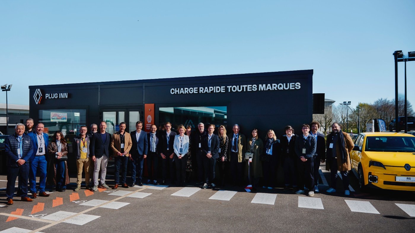Group photo in front of a Renault Group Plug Inn fast charging station.