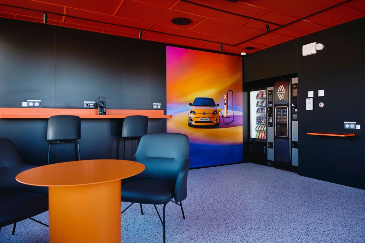 Modern lounge area with seating, table and illuminated screens in an exhibition space.