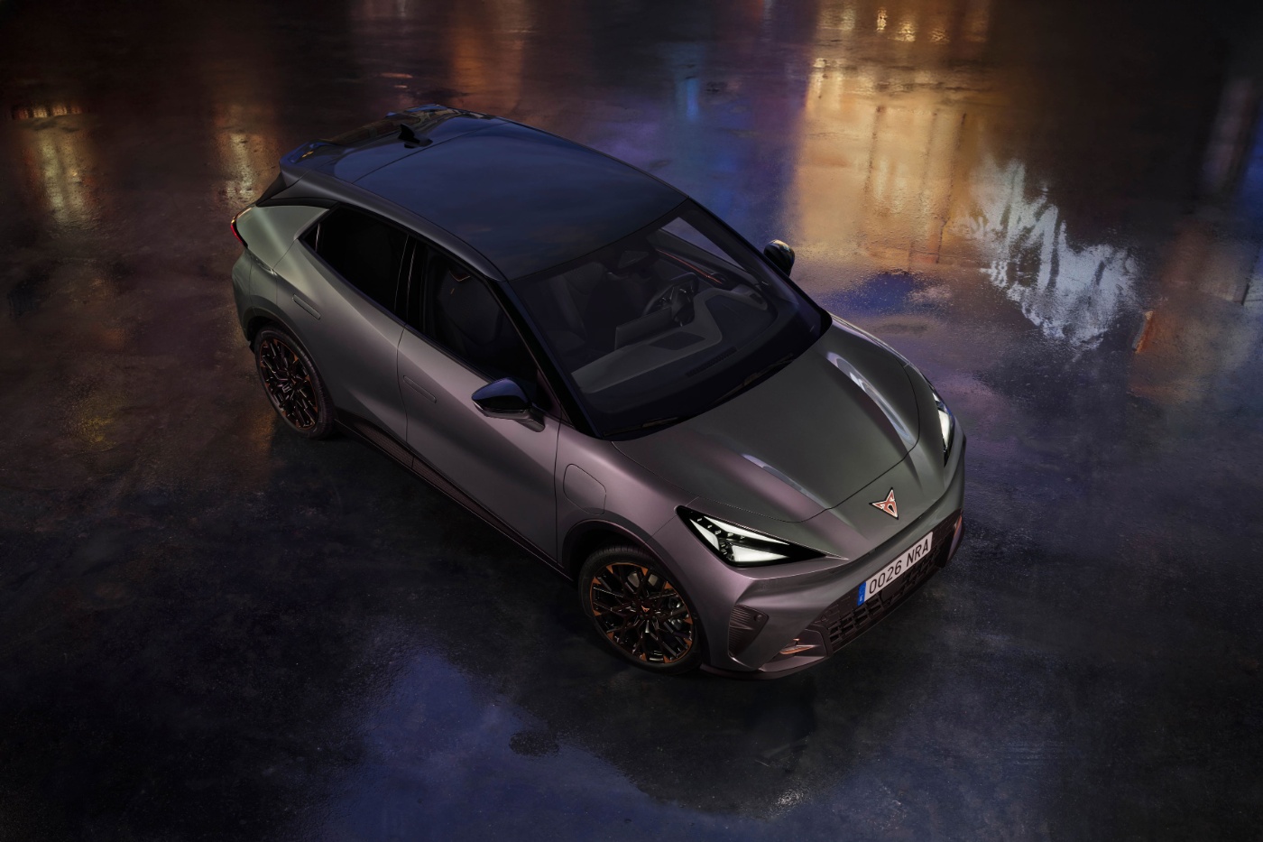 Dark green sports car parked on a wet surface at night with reflections.