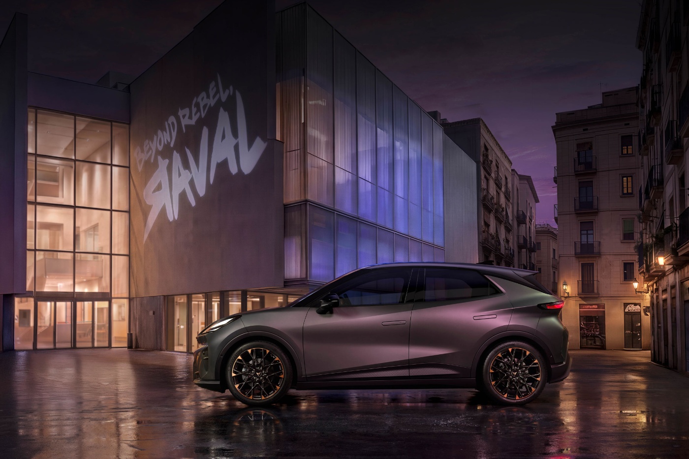 Electric car parked at night in front of a modern building with illuminated facade.