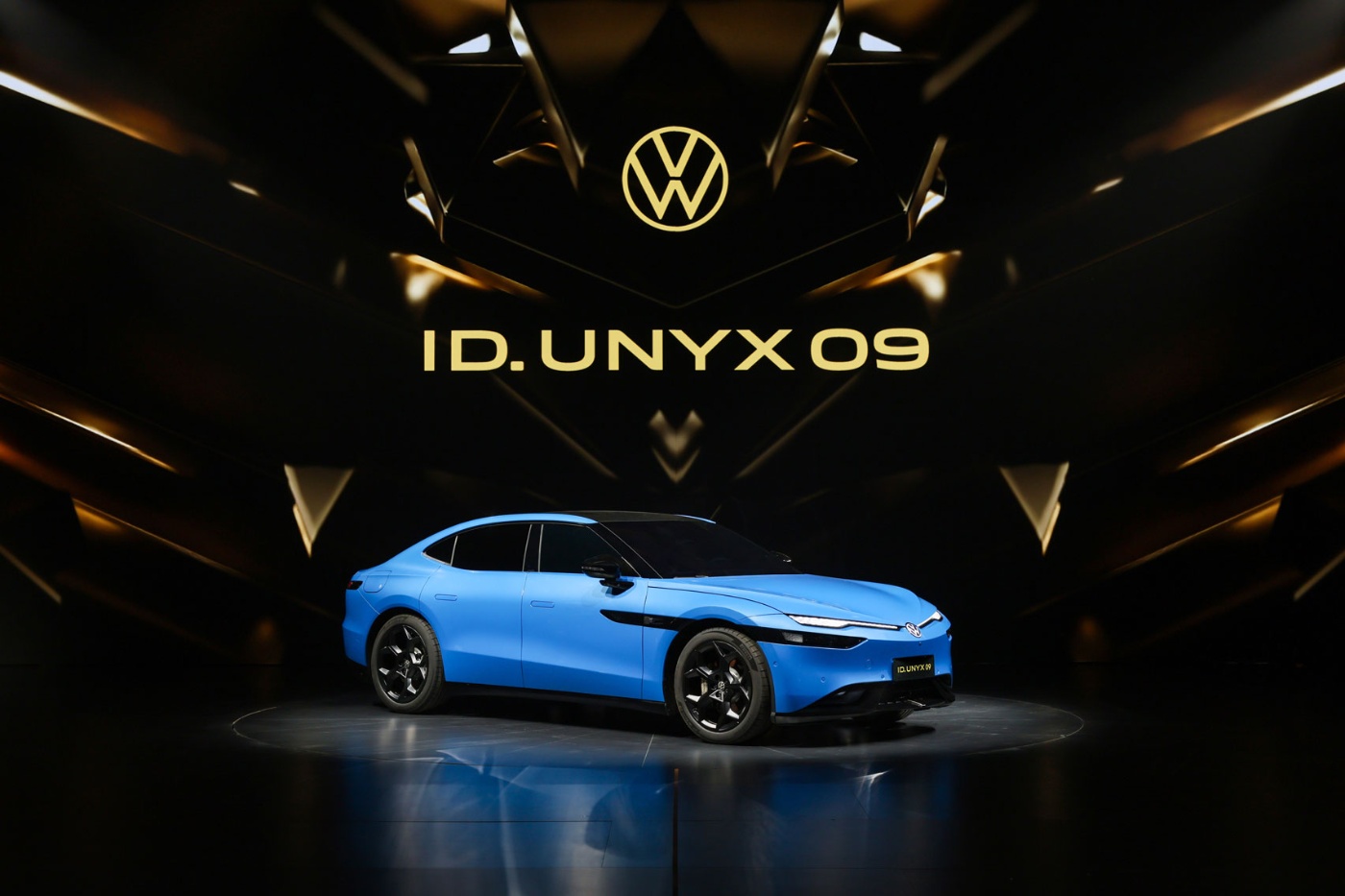 Blauer Volkswagen ID.UNYX 05 auf einer Bühne mit Logo darüber.