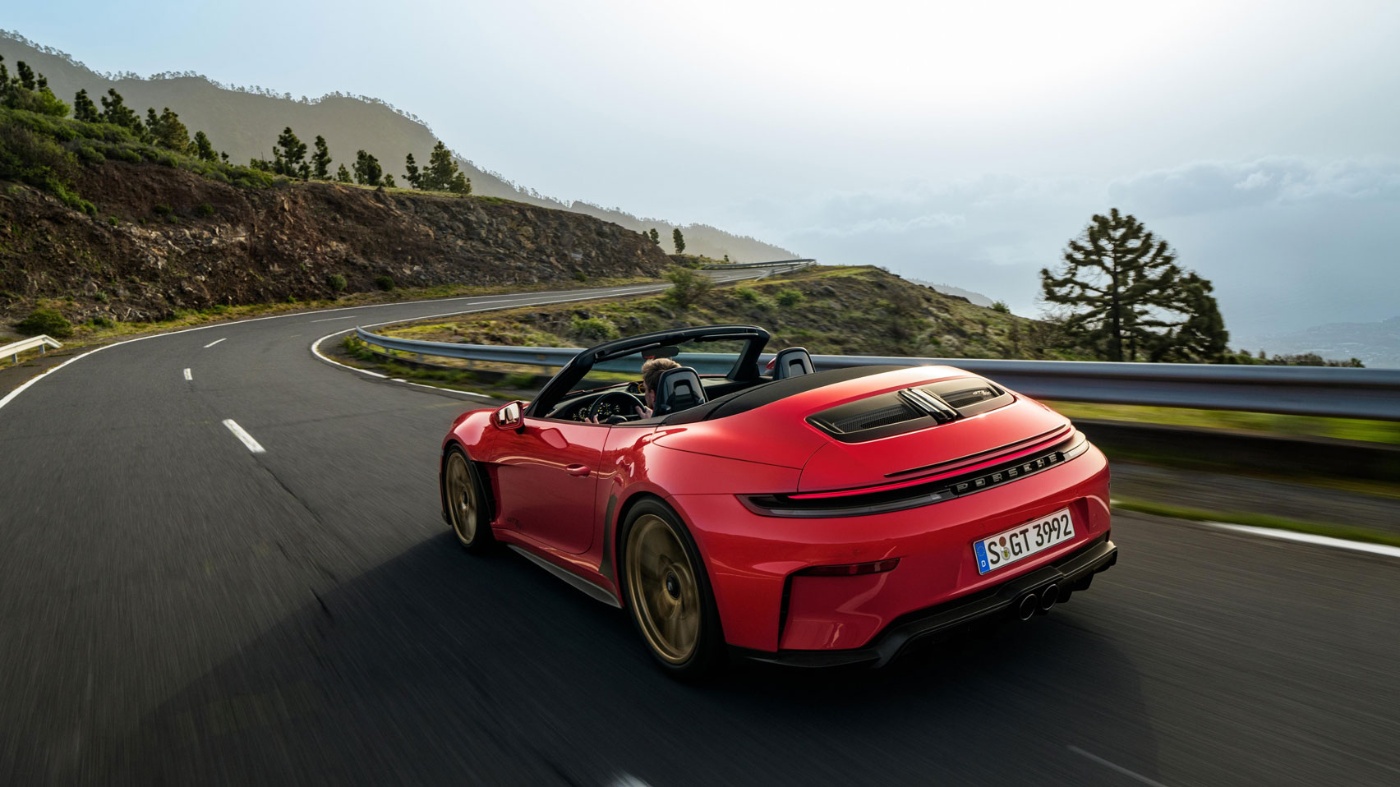 Heckansicht eines roten Porsche-Cabrios auf kurviger Bergstraße.