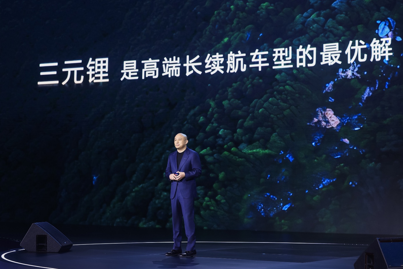 Man presenting on stage before screen with Chinese text.