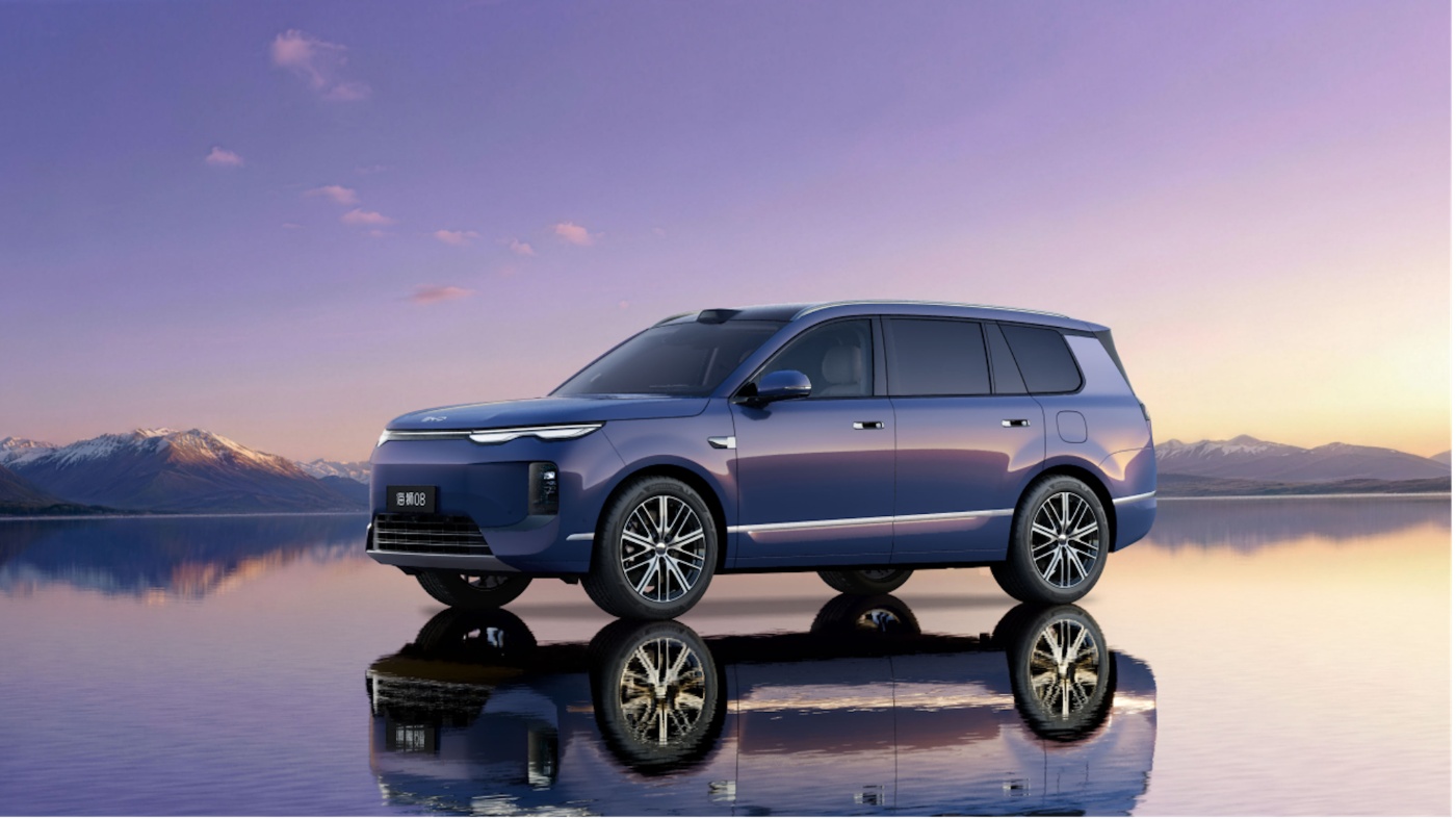 Blue SUV on a reflective surface with mountains at sunset.
