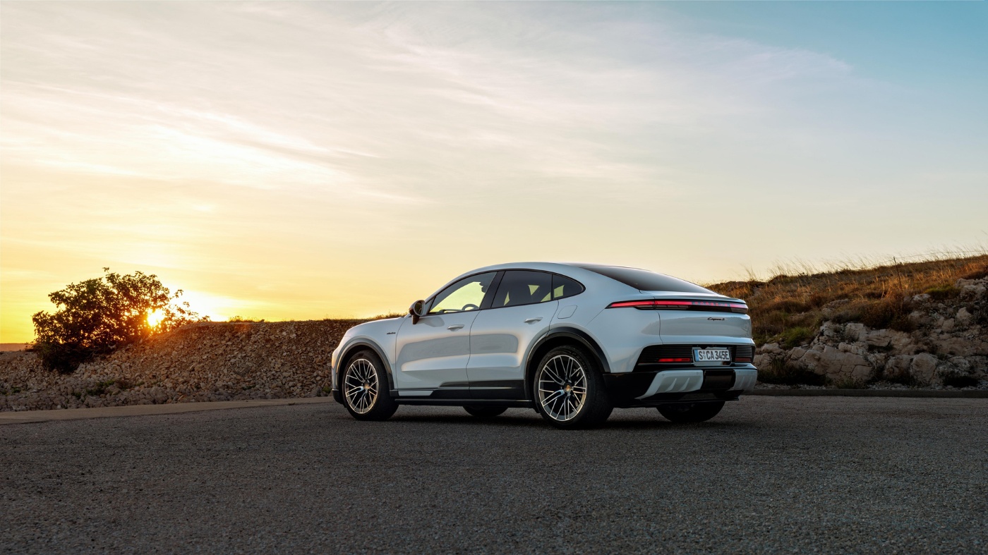 White Porsche parked on a road at sunset.