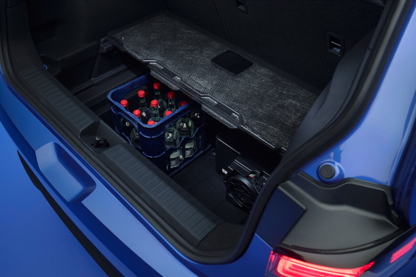 Open car trunk with a crate of glass bottles under a floor panel.