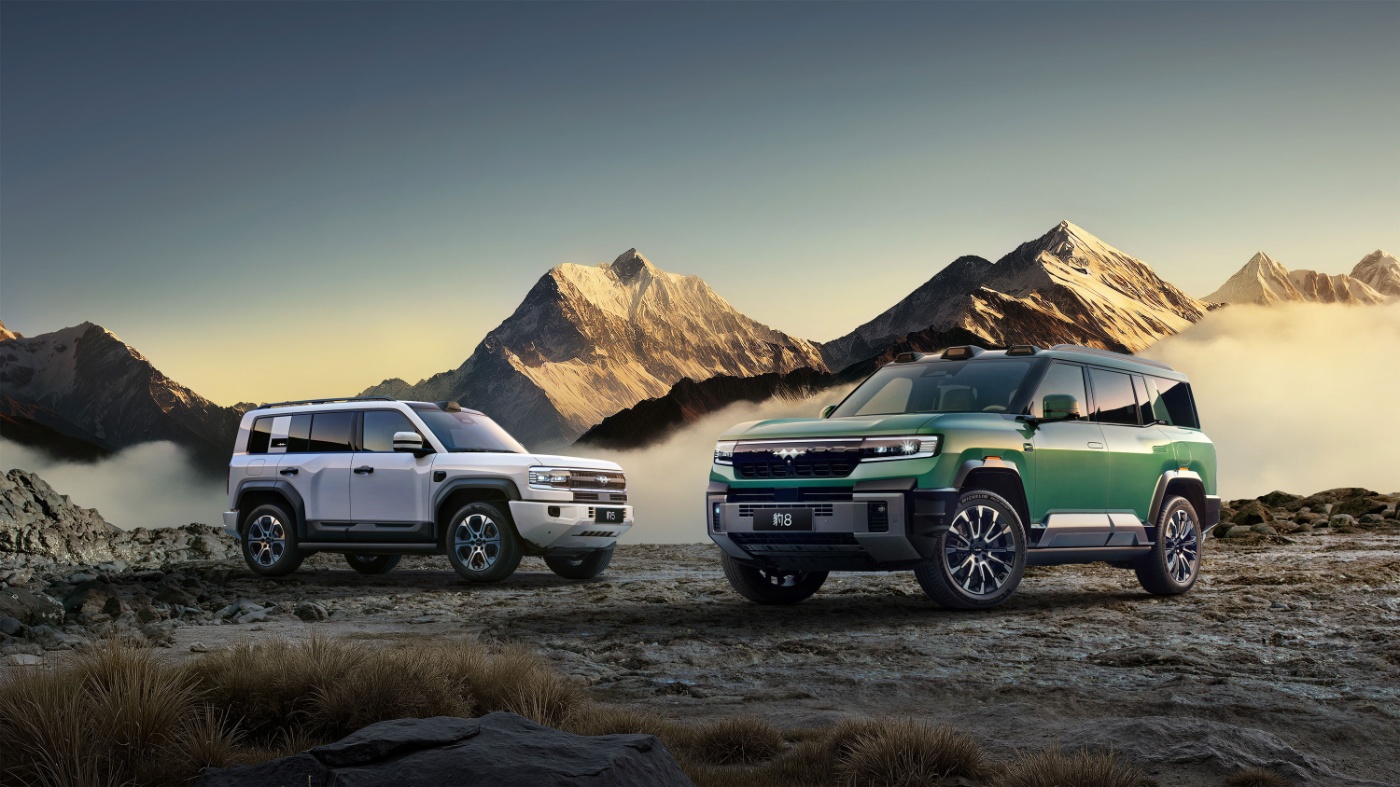 Two SUVs parked on rocky terrain with mountains at sunrise.