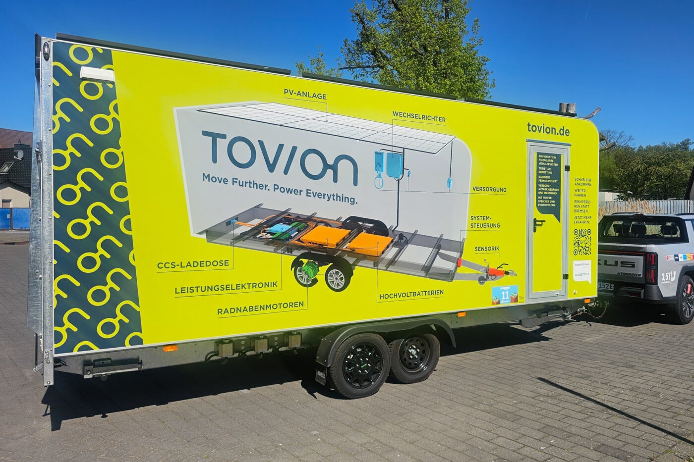 Gelber Tovion Anhänger mit Produktgrafik im Freien geparkt.